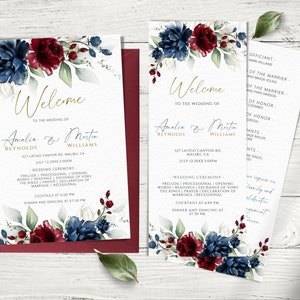 Peut inclure: Une suite d'invitation de mariage avec un motif floral aquarelle composé de fleurs bordeaux et bleues. L'invitation comprend les noms Amalia & Martin Reynolds & Williams, la date et l'heure du mariage, ainsi que le lieu. La carte de programme assortie comprend l'ordre de la cérémonie de mariage et les détails de la réception.