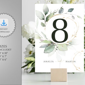 May include: A white wedding table number eight card with watercolor greenery and gold accents. The card includes the names "Amalia and Martin". The image also shows the text "Instant Download" and "3 Sizes Included: 8" x 10", 5" x 7", 4" x 6".