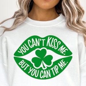 May include: White sweatshirt with a green graphic of lips, a shamrock, and the text "YOU CAN'T KISS ME, BUT YOU CAN TIP ME." The design is centered on the front of the sweatshirt.
