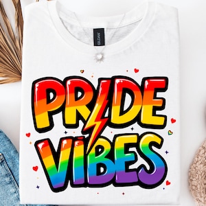 May include: White t-shirt with a rainbow-colored graphic that says "PRIDE VIBES" in a cartoon font. The graphic includes a lightning bolt.
