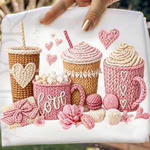 Puede incluir: Una tela blanca con una colección de tazas de café, tazas y una caja de regalo de punto. Las tazas y tazas son en tonos marrones y rosas, con detalles de corazón y "love". Bolas de hilo rosa y flores completan el diseño.