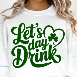 May include: White sweatshirt with green text that reads "Let's day drink" with a green shamrock inside a heart.