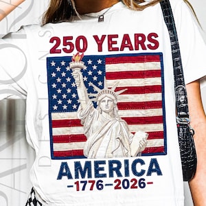 May include: White t-shirt featuring a graphic of the Statue of Liberty in front of an American flag. The text "250 YEARS AMERICA -1776-2026-" is printed above and below the image in red and blue.