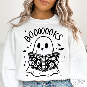 May include: White sweatshirt with a black and white illustration of a ghost reading a book. The text "BOO-OOOOKS" is above the ghost.