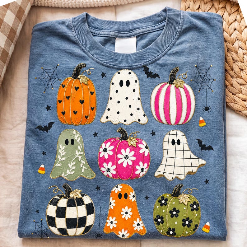 Op de afbeelding: Een blauw t-shirt met ronde hals voorzien van een grafische print van diverse pompoenen en geesten. De pompoenen tonen patronen zoals hartjes, strepen, bloemen en ruitjes. De geesten zijn voorzien van stippen, bloemranken en rasterpatronen.