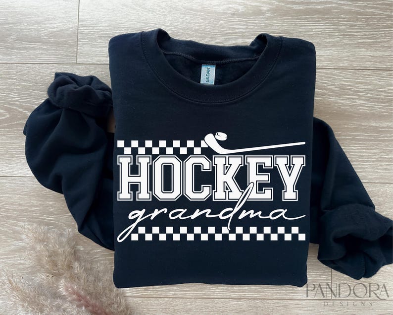 May include: Black sweatshirt with white text that reads "Hockey grandma" with a hockey stick and puck graphic.