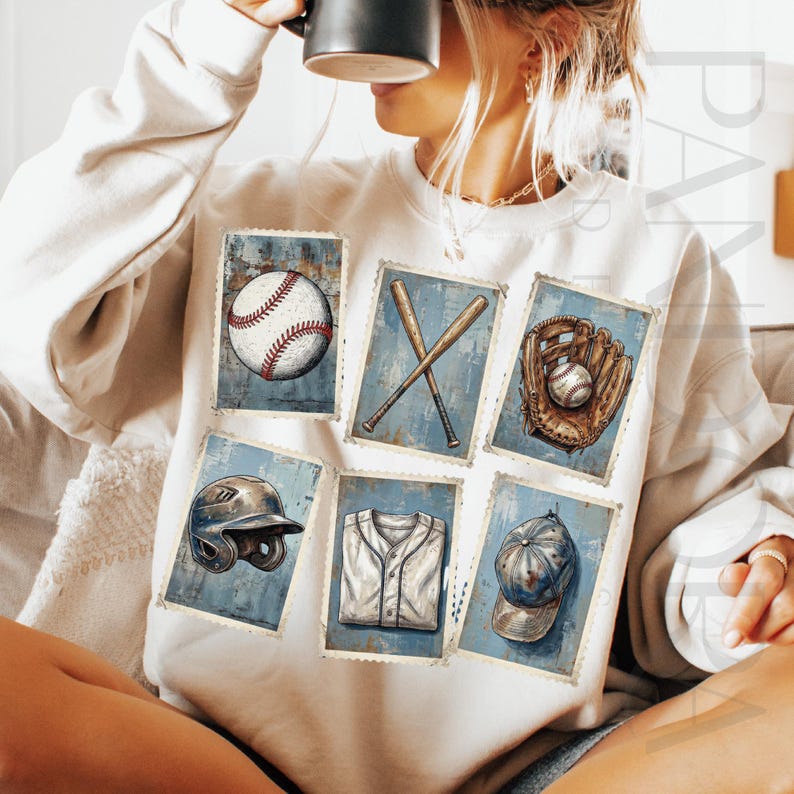May include: A white sweatshirt featuring six baseball-themed illustrations. The illustrations include a baseball, crossed bats, a glove with a ball, a helmet, a jersey, and a baseball cap. The illustrations are set against a blue background.