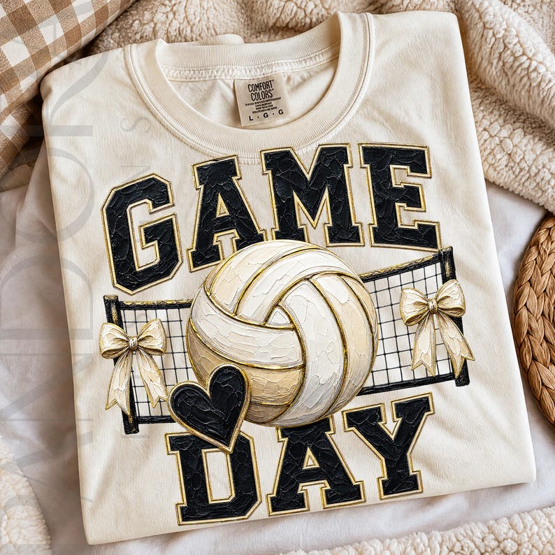 The phrase “Game Day” appears in large varsity-style lettering above and below a volleyball positioned in front of a volleyball net. Small decorative bows are attached to each side of the net, and a black heart accent appears near the bottom. The design uses a neutral palette of cream, black, beige, and gold tones, creating a stylish sports-themed graphic that combines volleyball spirit with a feminine boutique aesthetic.