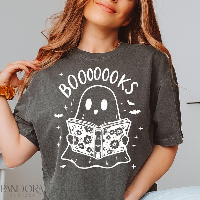 May include: A dark gray t-shirt with a white ghost holding a book with the text "BOO-OO-OO-OOKS" printed on it.