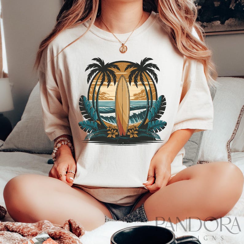 May include: A white t-shirt with a graphic of a surfboard and palm trees in a sunset scene. The graphic is in shades of blue, green, yellow, and orange.