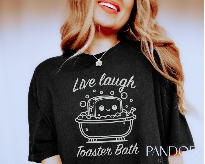 K&ouml;nnte beinhalten: Ein schwarzes T-Shirt mit einer wei&szlig;en Grafik einer Scheibe Brot in einer Badewanne mit Blasen und dem Text "Live laugh Toaster Bath".