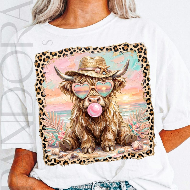 May include: White t-shirt featuring a whimsical illustration of a Highland cow wearing heart-shaped sunglasses, a straw hat, and blowing a bubble. The cow is set against a beach scene with a leopard print border. Seashells and tropical plants are also included.