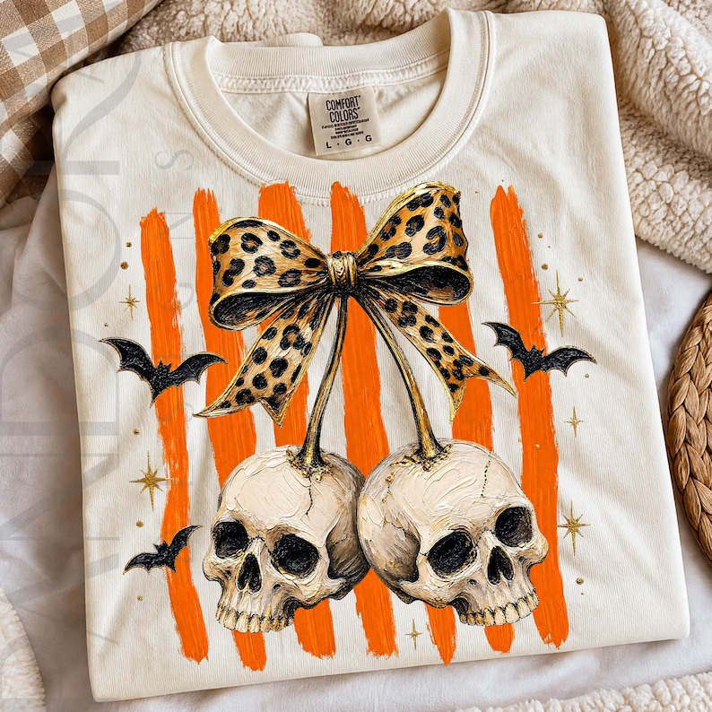 Two skulls hang like cherries under a leopard print bow, surrounded by orange brushstroke stripes, black bats, gold stars, and textured Halloween details.