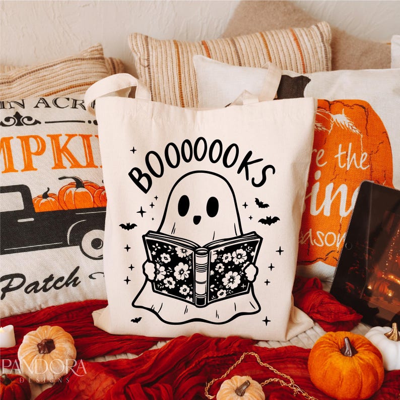 May include: A white tote bag with a black and white illustration of a ghost reading a book. The text "BOO0000KS" is above the ghost.