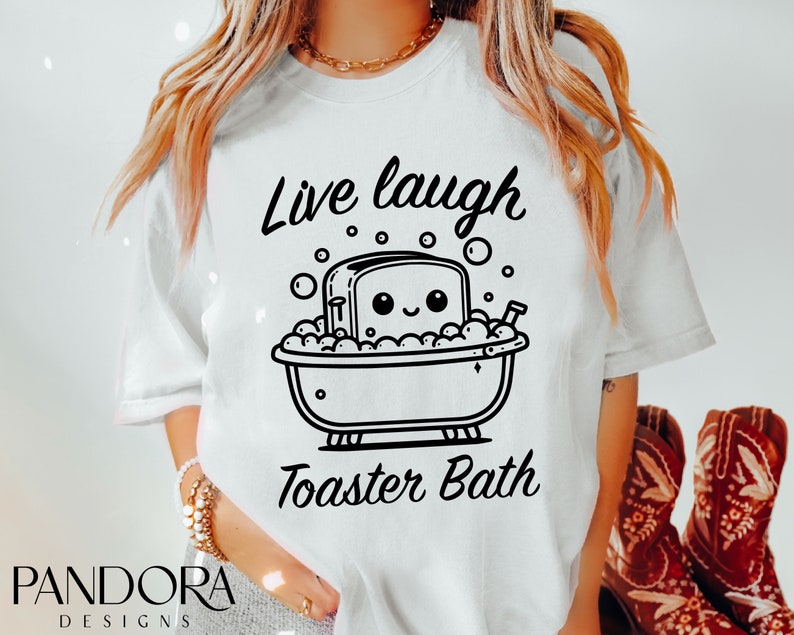 K&ouml;nnte beinhalten: Wei&szlig;es T-Shirt mit einer schwarz-wei&szlig;en Illustration eines Toasters in einer Badewanne mit Blasen. Der Text "Live laugh Toaster Bath" ist auf das T-Shirt gedruckt.