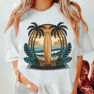 May include: White t-shirt with a graphic of a surfboard in front of a sunset with palm trees on either side.