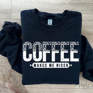 May include: Black sweatshirt with white text that reads "Coffee Makes Me Nicer" with a leopard print design.