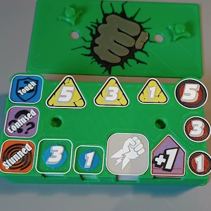 Puede incluir: Un tablero de juego de pl&aacute;stico verde con un gr&aacute;fico de pu&ntilde;o y varias fichas. Las fichas incluyen n&uacute;meros, s&iacute;mbolos y texto como "Tough", "Confused", "Stunned" y " +1".