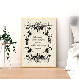 May include: A rectangular wall art print in a light wood frame featuring a cream-colored background with a black ornate filigree border. The text in the center reads: Tell me every terrible thing you ever did, and let me love you anyway.