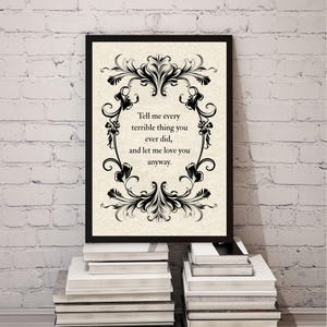 May include: A framed wall art print featuring a cream-colored background with a black ornate floral border. The text in the center reads: Tell me every terrible thing you ever did, and let me love you anyway. The frame is thin and black.