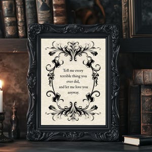 May include: A black ornate picture frame containing a cream-colored print with black decorative scrollwork borders. The text reads: Tell me every terrible thing you ever did, and let me love you anyway. The frame has intricate carved details.