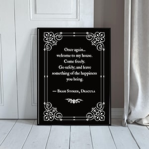 Könnte beinhalten: Schwarzer gerahmter Wandkunstdruck mit einem Zitat aus Bram Stokers Dracula. Das Zitat lautet: „Once again... welcome to my house. Come freely. Go safely; and leave something of the happiness you bring.“ Eine Fledermausgrafik befindet sich unten.