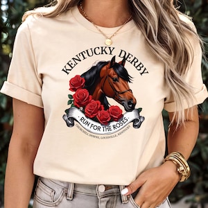 Peut inclure: Un t-shirt beige avec un motif représentant la tête d'un cheval brun avec une crinière noire et un bridon. Le motif est entouré de roses rouges et d'une bannière qui dit "Kentucky Derby - Run for the Roses - Churchill Downs, Louisville, Kentucky".