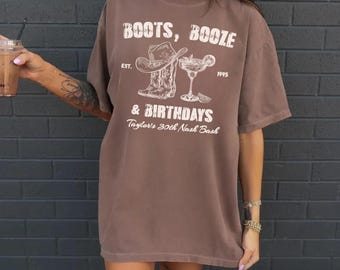 May include: Espresso brown oversized t-shirt with a white graphic print of cowboy boots, a margarita glass, and the text "Boots, Booze & Birthdays Taylor's 30th Nash Bash".