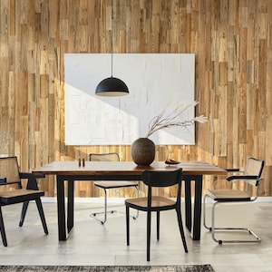 May include: A dining room scene featuring a dark wood table with black legs and several chairs. The chairs have woven seats and backs. A large white abstract artwork hangs on a wood plank wall. A black pendant light hangs above the table.