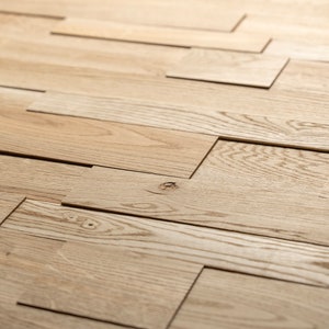 May include: A close-up of a wall made of light brown wood planks arranged in a staggered pattern. The planks are cut and arranged to create a unique and modern design.