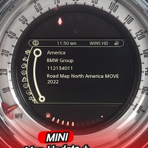 May include: A close-up of a car dashboard gauge with a digital display showing "America", "BMW Group", and "Road Map North America MOVE 2022". The gauge also displays the text "MINI Map Update + FSC Activation Code". The gauge is red and silver.