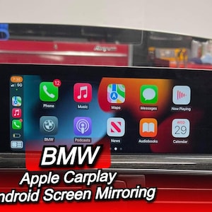 Op de afbeelding: Een rechthoekig scherm met de Apple CarPlay-interface in een BMW. Het scherm toont app-pictogrammen voor Telefoon, Muziek, Kaarten, Berichten en meer. De tekst "BMW Apple CarPlay Android Screen Mirroring" wordt eronder weergegeven.