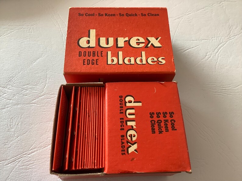Może przedstawiać: Zestaw oryginalnych, czerwonych pudełek z żyletkami Durex Double Edge. G&oacute;rne pudełko jest otwarte, ukazując ostrza i tekst "So Cool - So Keen - So Quick - So Clean". Logo Durex jest wyraźnie widoczne.
