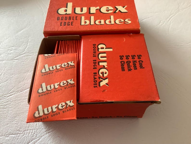 Może przedstawiać: Zestaw vintage ostrzy do golenia Durex z podw&oacute;jnym ostrzem w czerwonym opakowaniu. Pudełka i indywidualne opakowania ostrzy zawierają logo i tekst Durex. Opakowanie zawiera frazy "So Cool, So Keen, So Quick, So Clean."