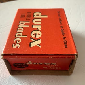 Może przedstawiać: Vintage pomarańczowe pudełko na ostrza Durex z podw&oacute;jnym ostrzem. Pudełko zawiera nazwę marki dużymi białymi literami, ze słowami "double edge blades" mniejszym tekstem. Pudełko zawiera r&oacute;wnież tekst "So Cool - So Keen - So Quick - So Clean".