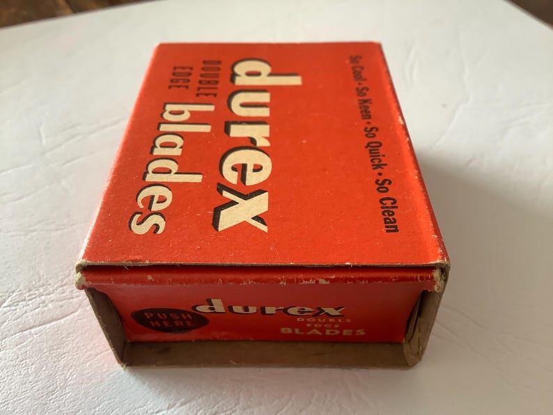 Może przedstawiać: Vintage pomarańczowe pudełko na ostrza Durex z podw&oacute;jnym ostrzem. Pudełko zawiera nazwę marki dużymi białymi literami, ze słowami "double edge blades" mniejszym tekstem. Pudełko zawiera r&oacute;wnież tekst "So Cool - So Keen - So Quick - So Clean".