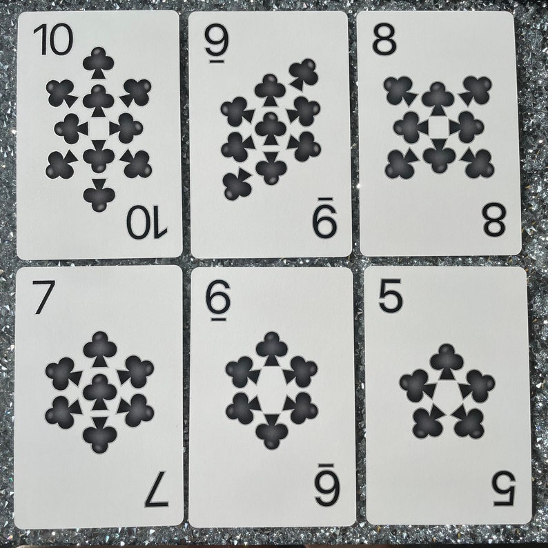 May include: A set of nine white playing cards with black clover symbols. The cards are numbered 5 through 10. The clover symbols are arranged in a star shape.