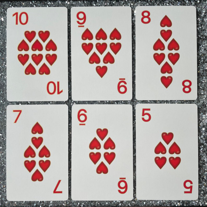 May include: Six playing cards with red hearts on a white background. The cards are numbered 5 through 10. The hearts are arranged in different patterns on each card.