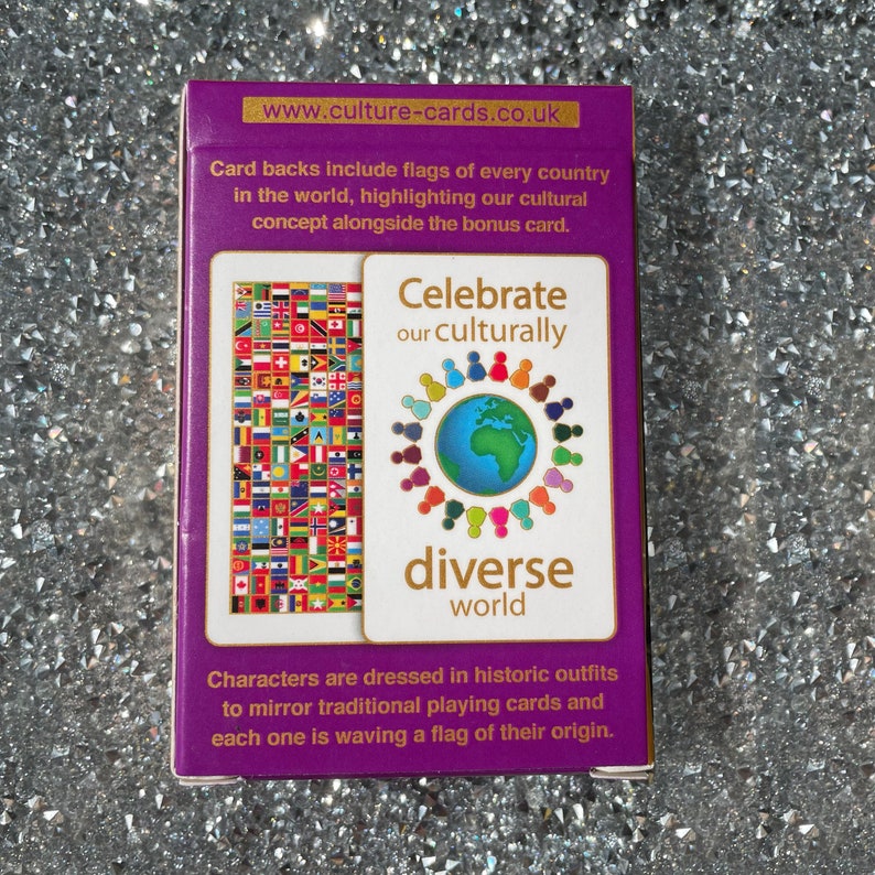 May include: A purple box with gold trim featuring a deck of playing cards. The box has the text "Celebrate our culturally diverse world" and shows a circle of people holding hands around a globe. The back of the cards features flags from around the world.