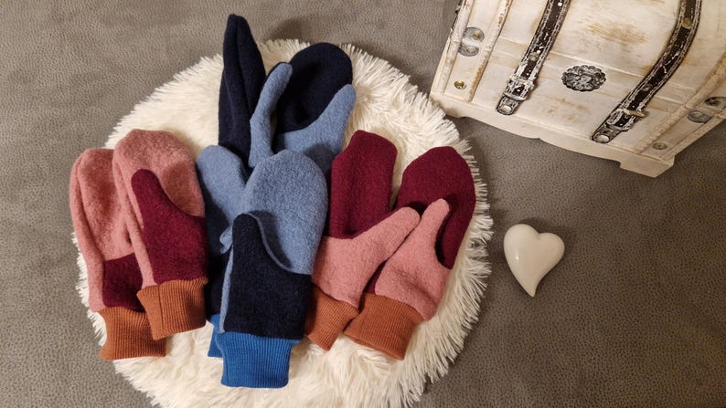 May include: Five pairs of colorful fingerless mittens with a contrasting color thumb and cuff. The mittens are made of a soft, fuzzy fabric and are perfect for keeping your hands warm in the winter.