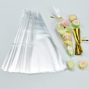 May include: A stack of clear plastic treat bags with a single bag filled with colourful candy and tied with gold ribbon.