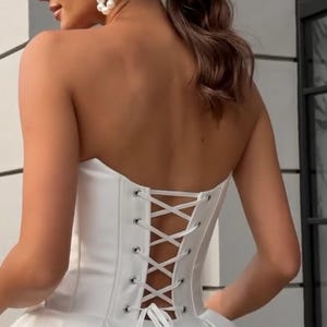 May include: A white strapless wedding dress with a corset back and a flowing skirt.