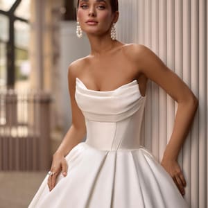 May include: A white strapless satin wedding dress with a fitted bodice and a flowing skirt.