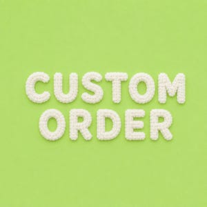 Könnte beinhalten: Die Wörter CUSTOM ORDER sind aus weißen, dreidimensionalen gehäkelten Buchstaben geformt. Jeder Buchstabe weist eine strukturierte Oberfläche aus Garn mit einem deutlichen Maschenmuster auf, angeordnet in zwei Reihen auf hellgrünem Grund.