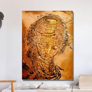 May include: A gold and brown abstract painting of a face with a halo. The painting is framed and hanging on a white wall in a living room setting.