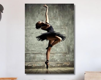 Könnte beinhalten: Ein Schwarzweißfoto einer Ballerina in einem schwarzen Tutu und Spitzenschuhen, die eine Pose auf einem Holzboden ausführt. Der Hintergrund ist eine strukturierte Wand mit einem verblassten, Vintage-Look.