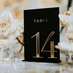 May include: Black table number card with gold lettering. The card reads "TABLE 14".