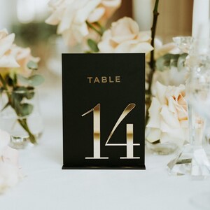 May include: Black table number card with gold lettering. The card reads "TABLE 14".