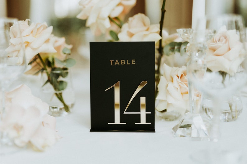 May include: Black table number card with gold lettering. The card reads "TABLE 14".
