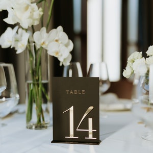 May include: A black table number card with gold lettering. The card reads "TABLE 14".